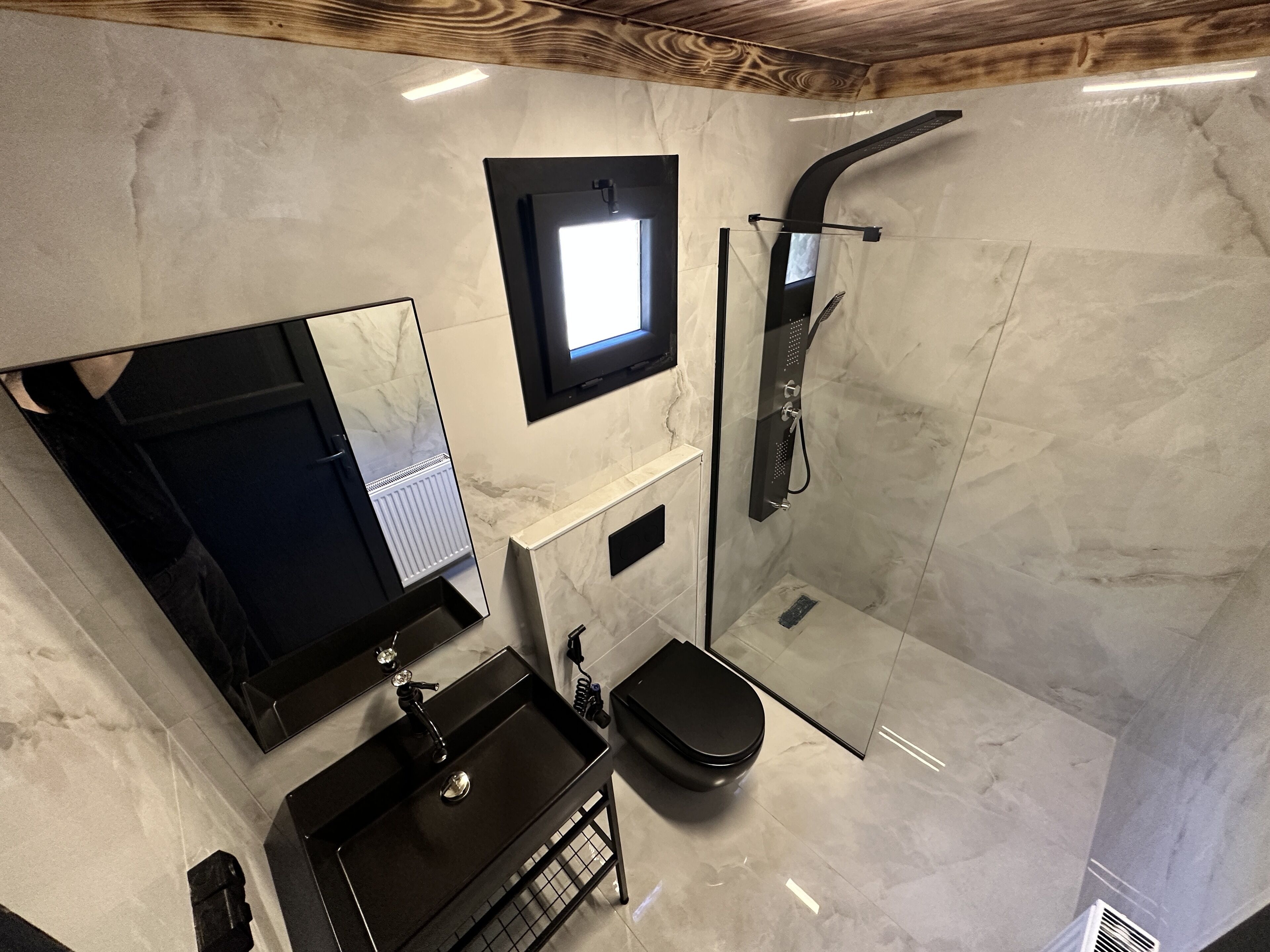 Un bagno moderno con uno specchio grande, un water, un lavabo e una doccia.