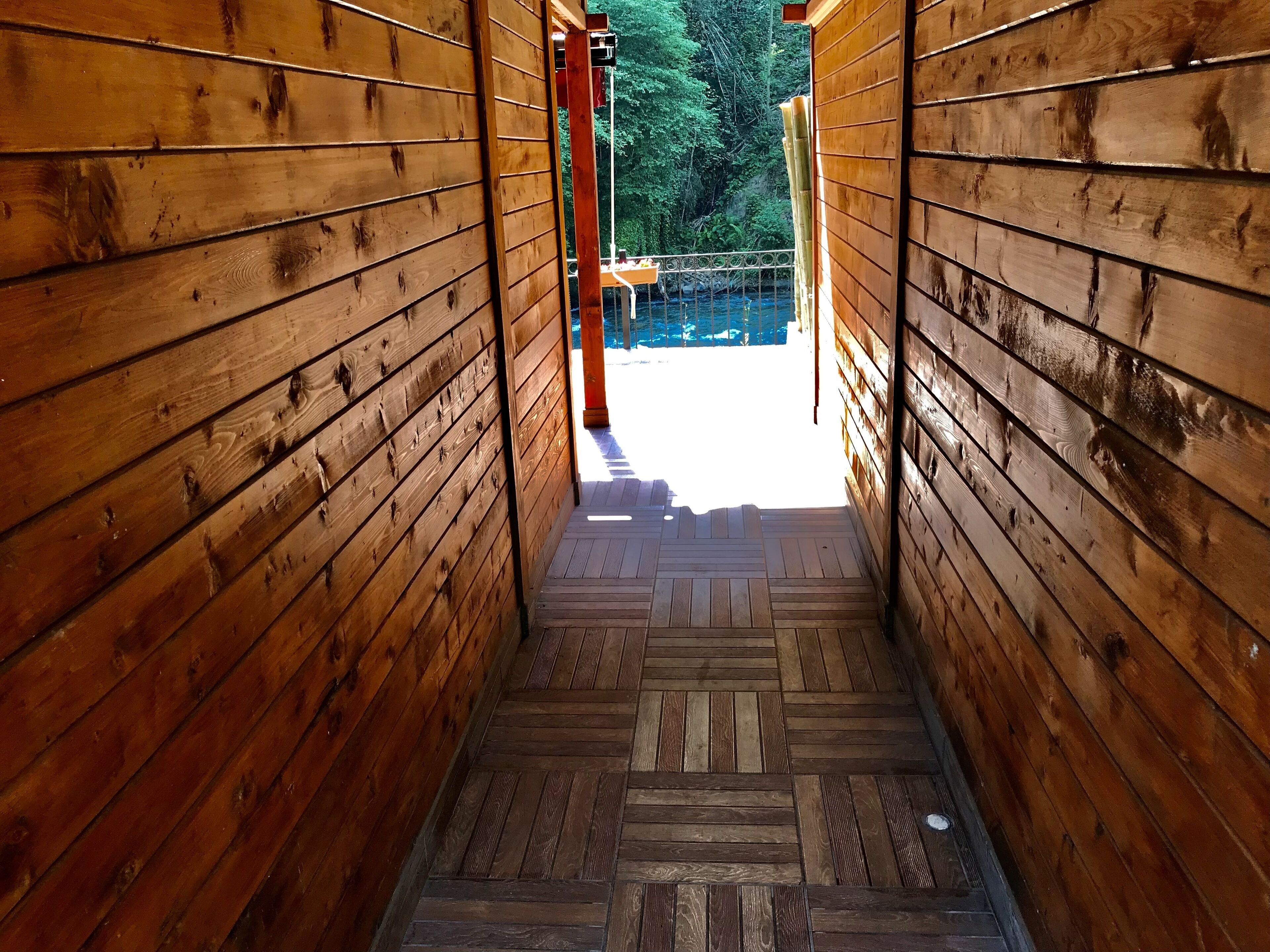 Una escalera de madera que lleva a un espacio exterior con vistas a árboles y una barandilla.
