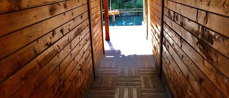 Una escalera de madera que lleva a un espacio exterior con vistas a árboles y una barandilla.