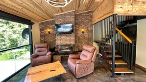 Un interior moderno con chimenea, sillones de cuero y techo de madera.