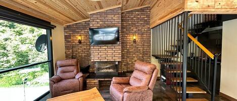 Un interior moderno con chimenea, sillones de cuero y techo de madera.