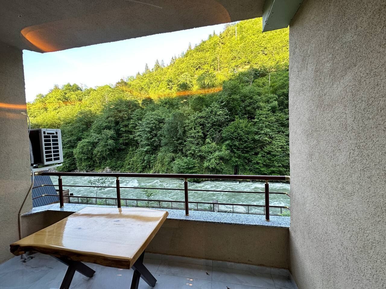 A balcony with a view of a river and forest.