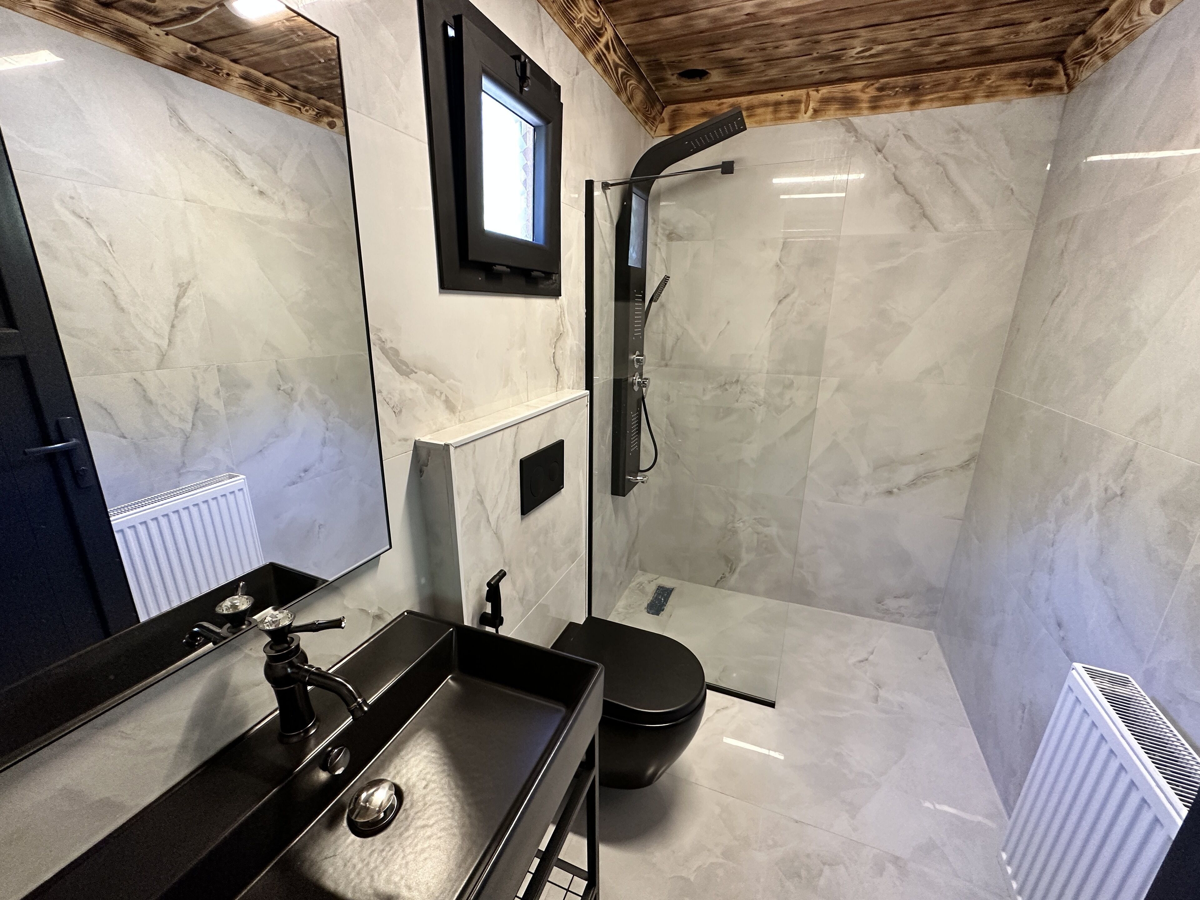 Un baño moderno con un lavabo negro, un inodoro y una zona de ducha.