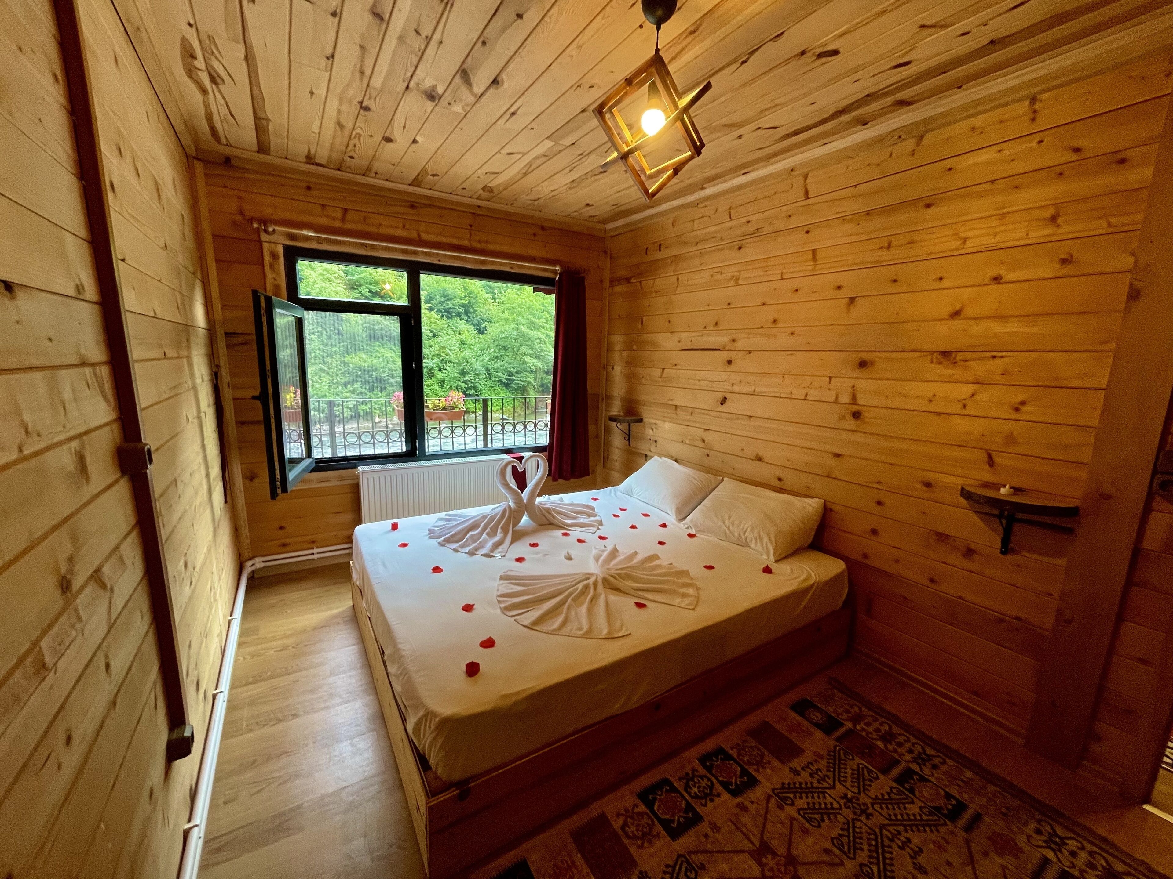 Ein Zimmer in einer Holzhütte mit einem Bett, einem Fenster und einem gemusterten Teppich.