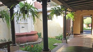 A covered outdoor area with a tiled floor, potted plants, and a round table. - Casa El Descansar (Antigua Guatemala)