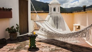A hammock on a rooftop terrace with a view of a mountain and a white building with a dome. - Casa Las Ruinas (Antigua Guatemala)