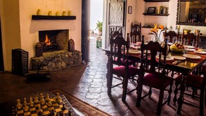 A dining area with a fireplace, chessboard, and a view of the outside. - Casa Las Ruinas (Antigua Guatemala)