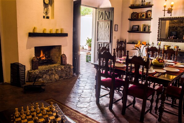 Un comedor con chimenea, un tablero de ajedrez y vistas al exterior.