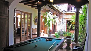 A pool table in a covered outdoor area with a patio and seating. - Casa Real (Antigua Guatemala)
