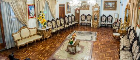 A grand room with ornate furniture, a chandelier, and a herringbone floor pattern.