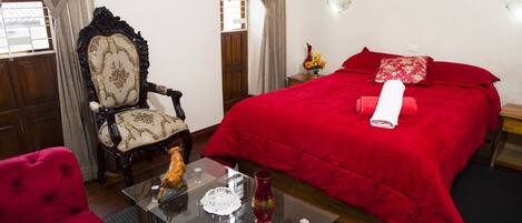 Una habitación de hotel con una cama, una silla, una mesa y un florero con flores.