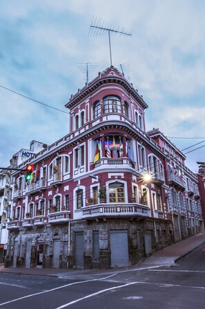 A historic building with a balcony, a sign indicating it is a hotel, and multiple flags. - Hotel Plaza del Teatro (Quito)