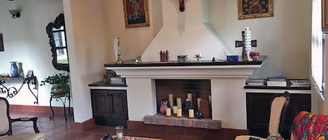 A living room with a fireplace, a cross, and religious paintings.
