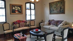 A cozy living room with a sofa, chairs, a coffee table, and artwork on the walls. - Casa Del Calvario (Antigua Guatemala)