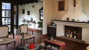 A cozy living room with a fireplace, comfortable seating, and a cross on the wall. - Casa Del Calvario (Antigua Guatemala)
