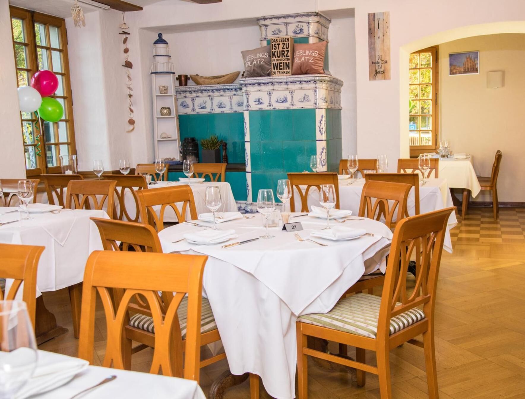 Ein Restaurant mit Holztischen und -stühlen, einer blau-weißen Fliesenwand und einem Schild mit der Nummer 21 auf dem Tisch.