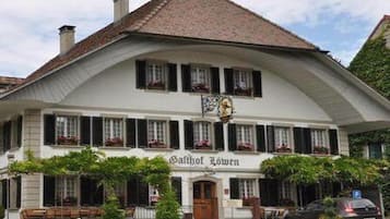 Traditional building with a central entrance and charming windows, surrounded by lush greenery.