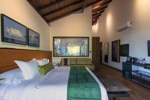 A modern hotel room with a large bed, a sofa, a dining area, and artwork on the walls. - Kûara Hotel (Porto Seguro)