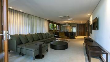 A modern living room with a sectional sofa, a round coffee table, and a TV mounted on the wall.
