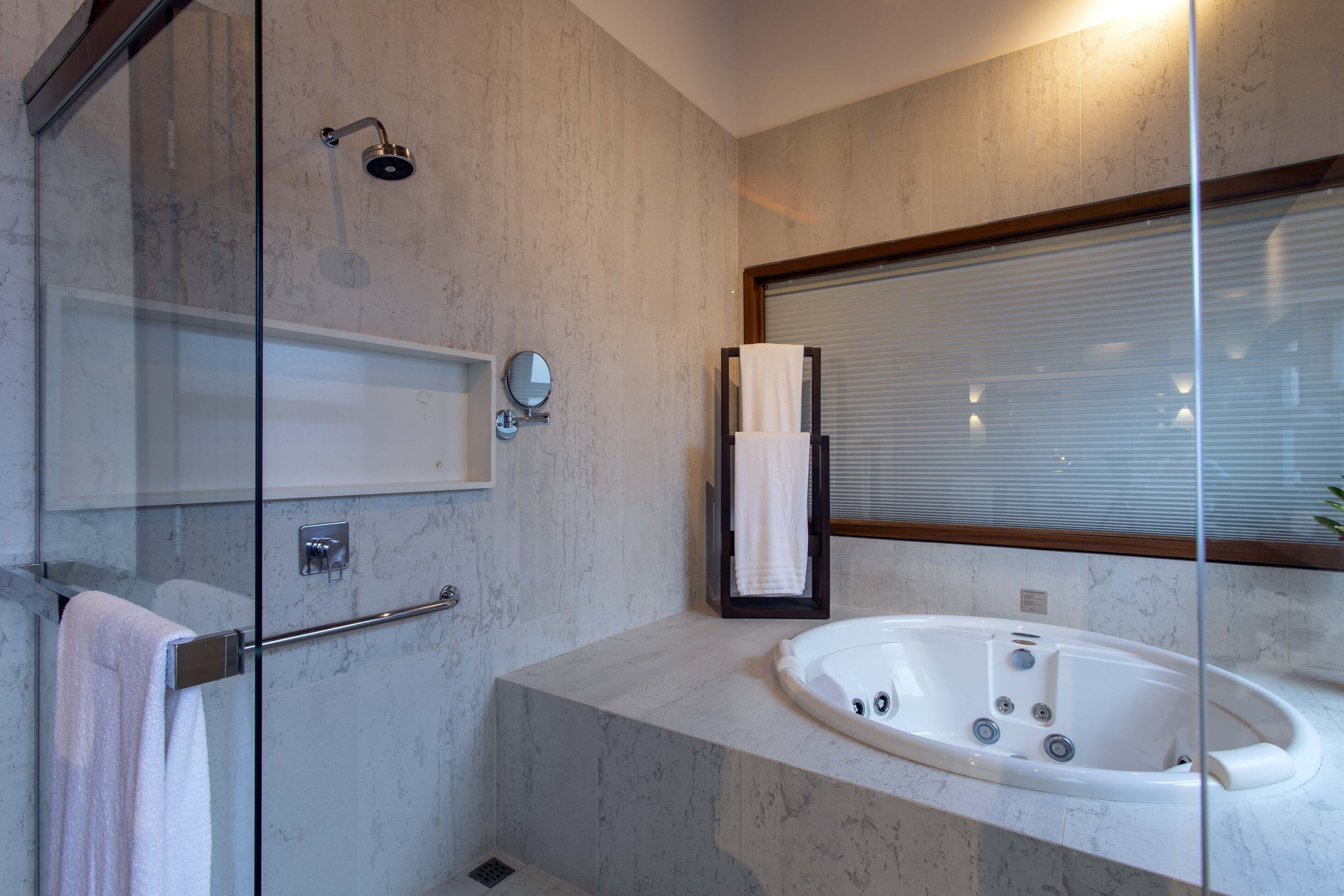 Een moderne badkamer met een douchecabine van glas, een vrijstaand bad en een grote spiegel.