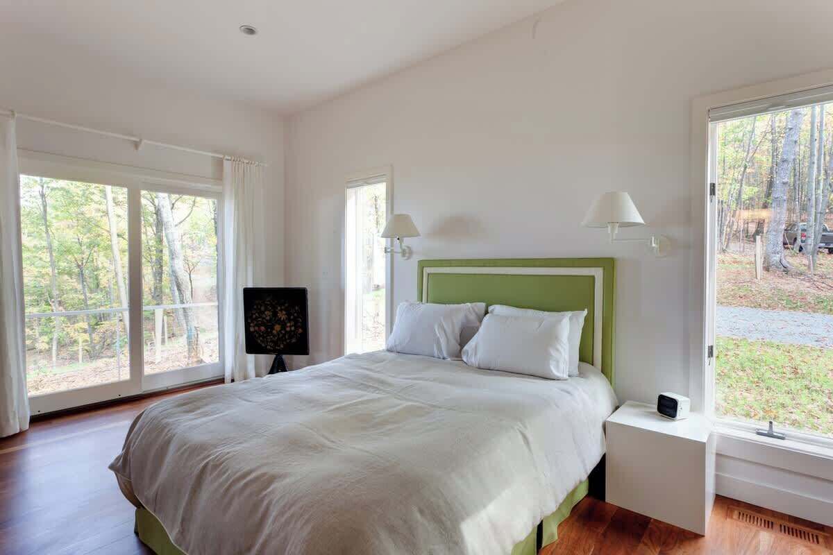 Camera da letto con un letto grande, due lampade ai comodini, un comodino e una finestra con vista sugli alberi.