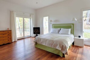 A bedroom with a bed, a dresser, a nightstand, a lamp, and a window.