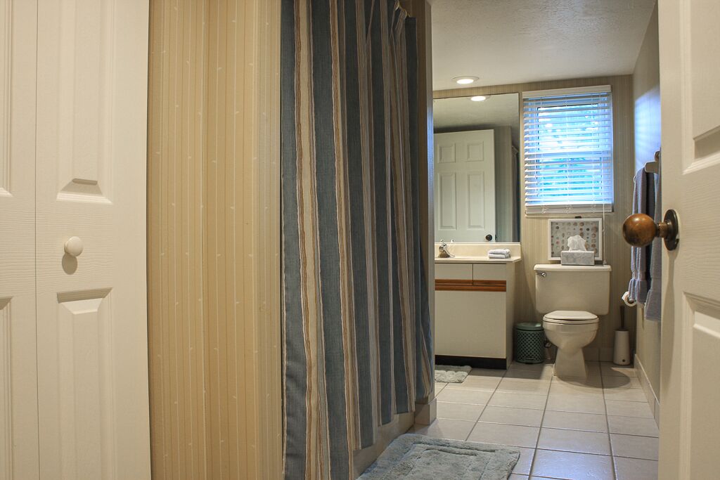 A bathroom with a toilet, sink, and shower curtain.