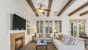Una sala de estar con chimenea, un sofá, una mesa de centro y un televisor montado en la pared.