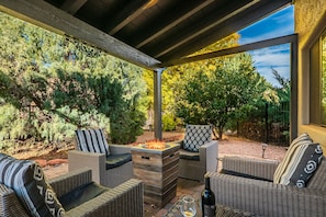Relax in a shaded patio surrounded by lush greenery and enjoy the warmth of a fire feature.