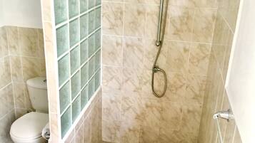 A bathroom with a shower, toilet, and a tiled wall.