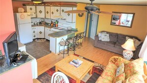 Un espace de vie compact comprenant un coin cuisine, un coin repas et un espace détente avec un canapé et des fauteuils.
