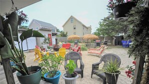 Un jardin avec des meubles d’extérieur, des plantes en pot et un espace barbecue.