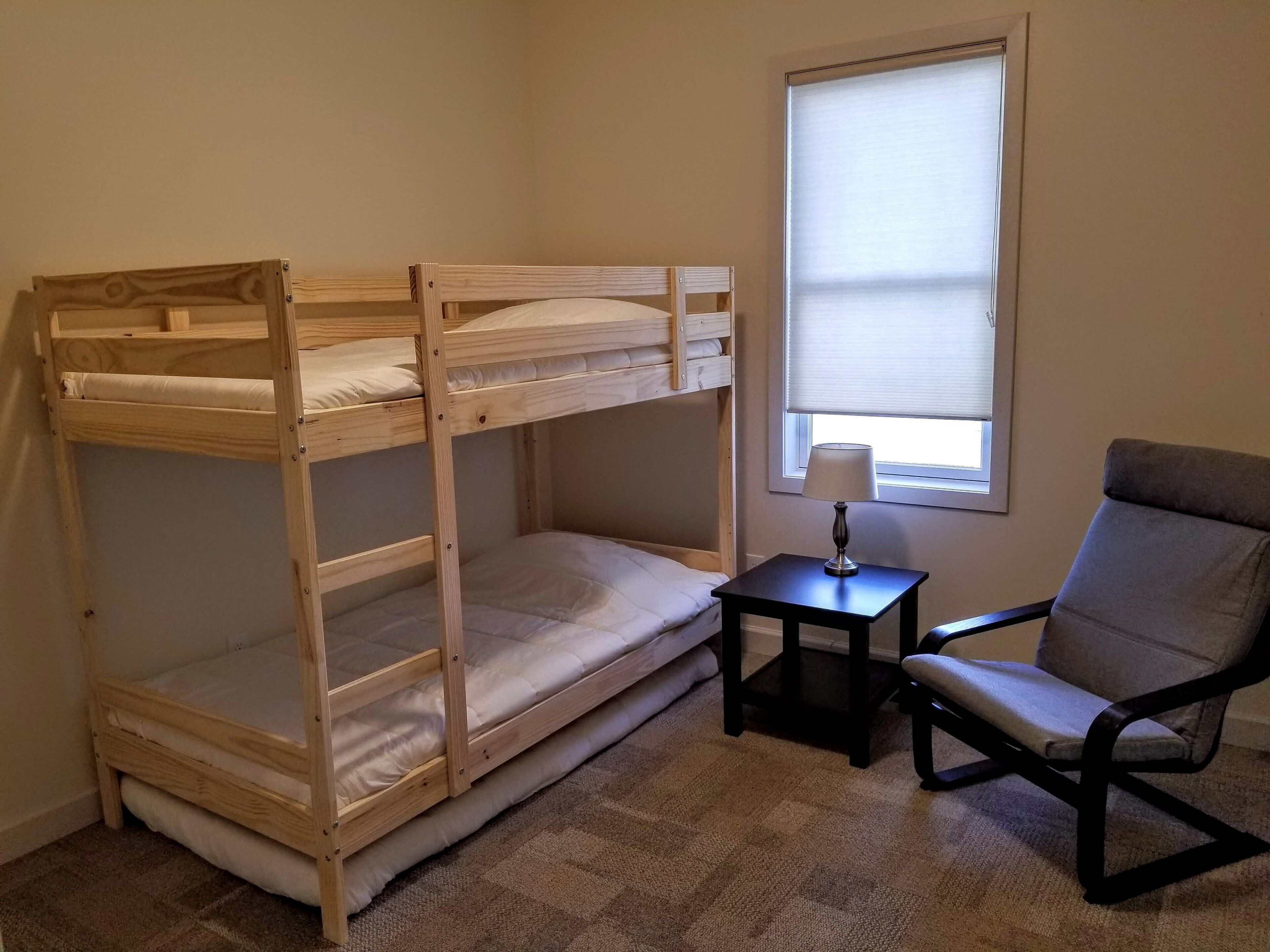 A bunk bed room with a small table and a chair.