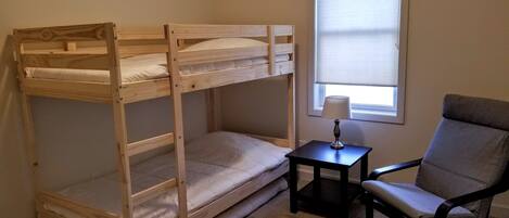 A bunk bed room with a small table and a chair.