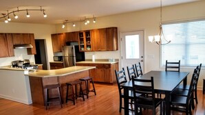 A modern kitchen with wooden cabinets, a stainless steel refrigerator, and a central island with stools.