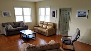 A living room with a brown leather sofa, a grey sofa, a coffee table, and a black chair.