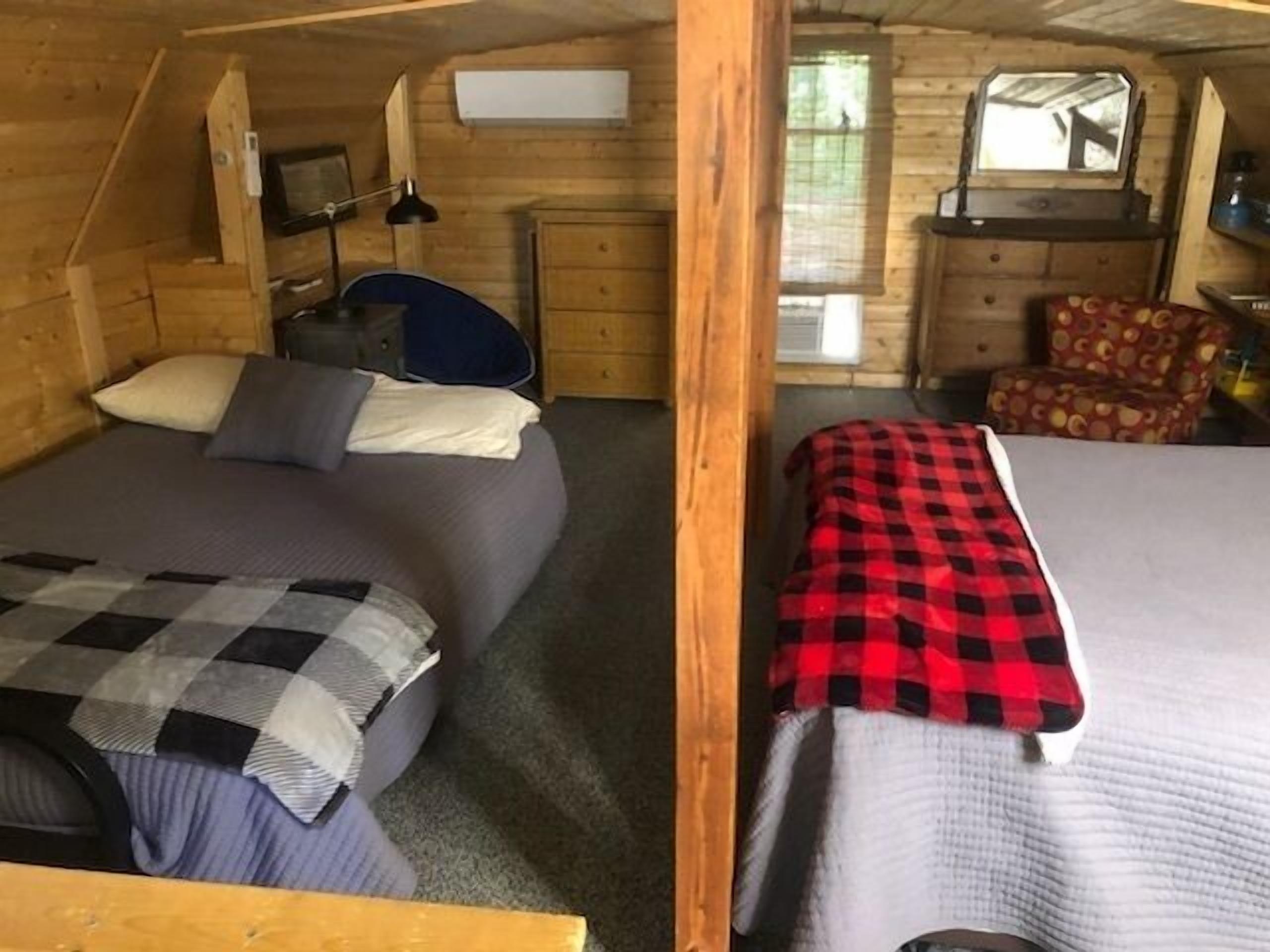 Una cabaña con dos camas, un escritorio pequeño, una silla y una ventana.