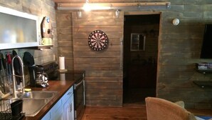 A kitchen with wooden walls, a dartboard, and a TV. - The Barn - Only 5 minutes to I65 (Montevallo)