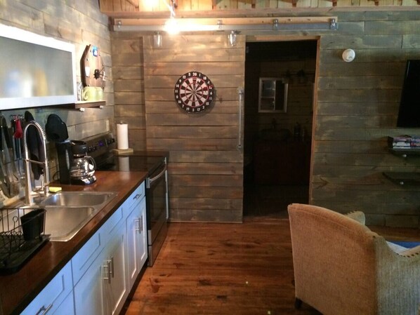 A kitchen with wooden walls, a dartboard, and a TV.