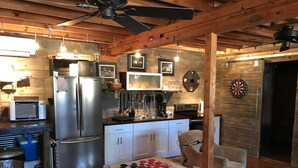 A rustic kitchen with wooden beams, a refrigerator, a microwave, and a dartboard. - The Barn - Only 5 minutes to I65 (Montevallo)