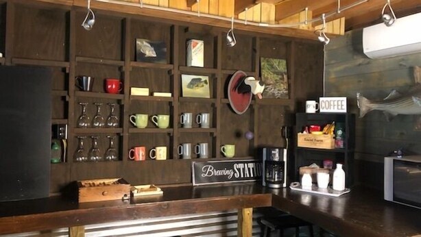 A rustic bar area with wooden shelves displaying mugs and glasses, a coffee station, and a sign reading "Brewing Station". - The Barn - Only 5 minutes to I65 (Montevallo)