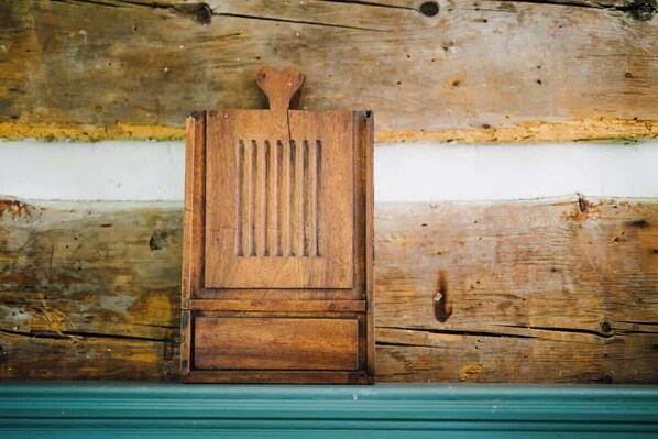 Un objet en bois composé de lattes verticales et surmonté d’une forme en cœur, le tout sur un fond en bois rustique.