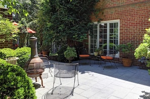 A patio with outdoor seating, a brick wall, and potted plants.