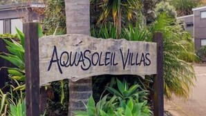 A wooden sign with the text "AQUASOLEIL VILLAS" indicating the name of a property.