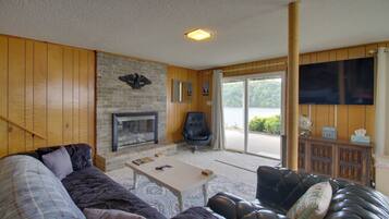 A living room with a fireplace, leather sofas, a coffee table, and a television mounted on the wall.