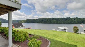 A lakeside property with a covered deck, a small shed, and a lawn with a flagpole.