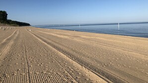 A wide sandy beach with a clear blue sky and calm sea. - Brower Cottage - Lakefront Secluded Wooded Lot on Hutchins Lake Near Saugatuck (Fennville)