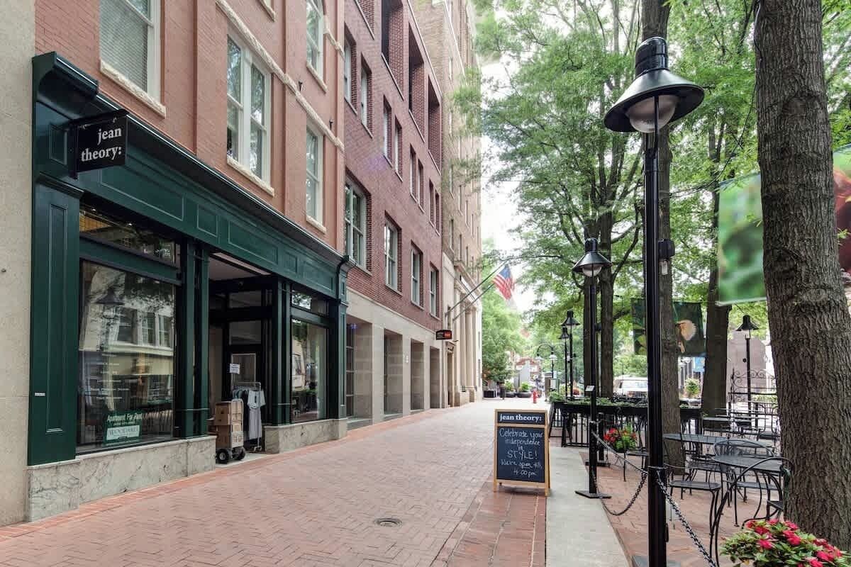 A brick building with a storefront named 'jean theory' and a sidewalk with outdoor seating.