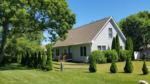 A single-story house with a sloped roof, a front porch with a railing, and a well-maintained lawn. - Beautiful 3 bedroom  2 bath Home / Close to Town & Beach (Oak Bluffs)