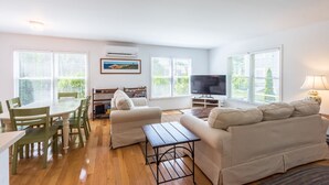 A spacious living room with a dining table, two sofas, a TV, and a fireplace. - Beautiful 3 bedroom  2 bath Home / Close to Town & Beach (Oak Bluffs)